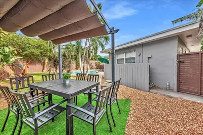 a table and chairs in the backyard of a house at Sunny Days Getaway, 5BD Heated Pool Family Home! in Fort Lauderdale