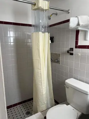 a bathroom with a shower curtain and a toilet at Vacation Inn motel - FT Lauderdale Airport and Cruise port in Fort Lauderdale