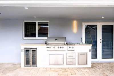 a white outdoor kitchen with a stove and windows at Gables Paradise - Htd Pool,5 Bdrooms ,Mini Golf, Playground, Baby Items, BBQ in Tamiami