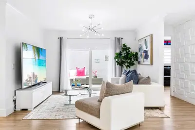 a white living room with a white couch and a tv at Gables Paradise - Htd Pool,5 Bdrooms ,Mini Golf, Playground, Baby Items, BBQ in Tamiami