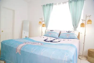 a bedroom with a bed with blue sheets and a window at Miami New Beach Stay 3 min to Ocean in Miami Beach