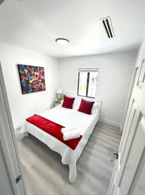 a white bedroom with a bed with red pillows at Stay Where Miami Comes Alive in Miami