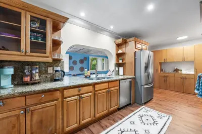 a kitchen with wooden cabinets and a stainless steel refrigerator at Centrally Located 4BD Oasis with Pool & Movie Patio in Hollywood