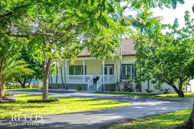 a white house with trees in front of it at Lake Of Dreams Miami House in Miami