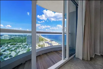 a room with a balcony with a view of the ocean at Beachfront Condo Fort Lauderdale in Fort Lauderdale