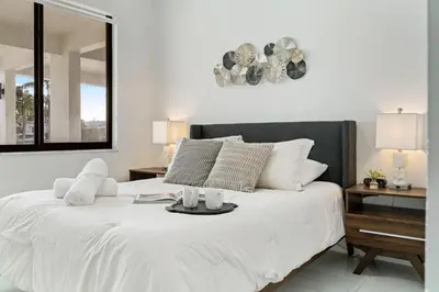 a bedroom with a white bed with a black headboard at April Sale! 4BR - Private Yard, Grill, Soaking Tub, Near Coral Gables & MIA Airport in Tamiami