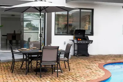 a table and chairs with an umbrella next to a pool at April Sale! 4 BR - Private Pool, Grill, Soaking Tub, Near Coral Gables & MIA Airport in Miami