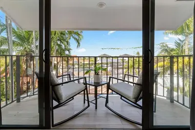 a balcony with chairs and a table and palm trees at April Sale! 4 BR - Private Pool, Grill, Soaking Tub, Near Coral Gables & MIA Airport in Miami