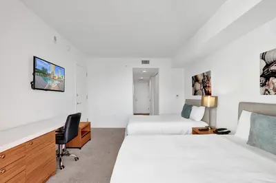 a hotel room with two beds and a desk at Beachwalk Resort in Hallandale Beach