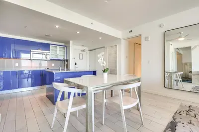 a kitchen with blue cabinets and a glass table and chairs at Walk to Beach and Dining! Luxe Fort Lauderdale Condo in Fort Lauderdale