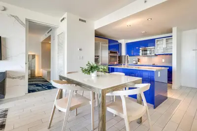 a kitchen with blue cabinets and a table and chairs at Walk to Bars and Eats! Luxe Ft Lauderdale Condo in Fort Lauderdale