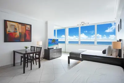 a bedroom with a bed and a desk with a table at Castle 732 Ocean View with pool, tennis, beach access, FREE parking in Miami Beach