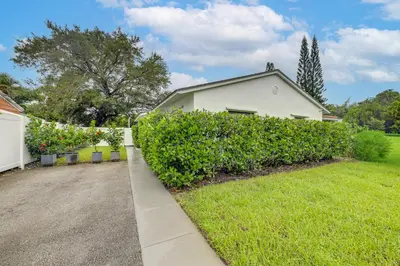 a yard with a white house and a hedge at The Peacock Bungalow Near Fort Lauderdale Beach! in Fort Lauderdale