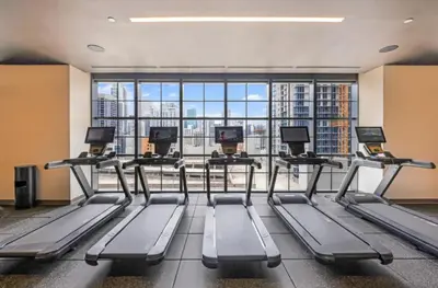 a gym with several treadmills and a large window at Lux 48th Floor Condo, Water views, Pool, Gym and Spa in Miami