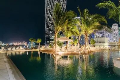 a pool with palm trees and a city at night at Lux 48th Floor Condo, Water views, Pool, Gym and Spa in Miami
