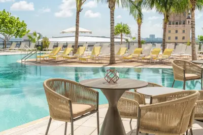 a table and chairs next to a swimming pool at Lux 48th Floor Condo, Water views, Pool, Gym and Spa in Miami