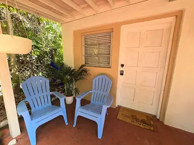 two blue chairs sitting on a porch with a door at Hidden Tropical Gem Calle Ocho 1 in Miami