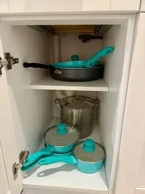 a cupboard with a pot and a pan and a whisk at New comfortable and youthful sport in Fort Lauderdale