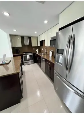 a large kitchen with a stainless steel refrigerator at Spacious 3 BR plus 1 office and 2 BA with Free parking Just in front beach in Sunny Isles Beach