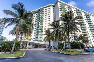 a large building with palm trees in a parking lot at Spacious 3 BR plus 1 office and 2 BA with Free parking Just in front beach in Sunny Isles Beach