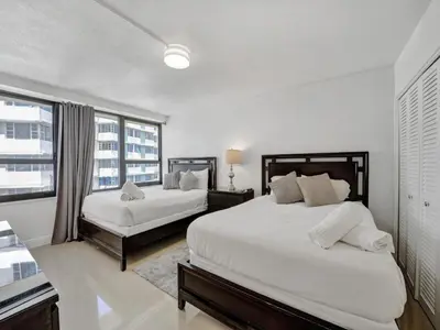 a white bedroom with two beds and a window at Charming Ocean View Condo with Beach Service 1516 in Miami Beach