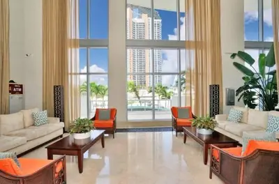 a living room with couches and chairs and large windows at 1BR Apartment with Ocean View in Sunny Isles Beach
