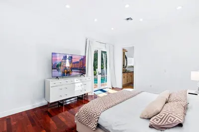 a white bedroom with a large bed and a flat screen tv at Luxurious 5BR and 3BA Lakefront Villa near Beach in Hollywood