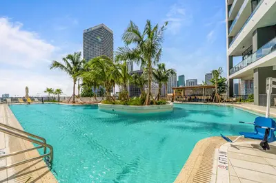 a large swimming pool with palm trees and buildings at 48Flr Condo w Free Parking in Miami
