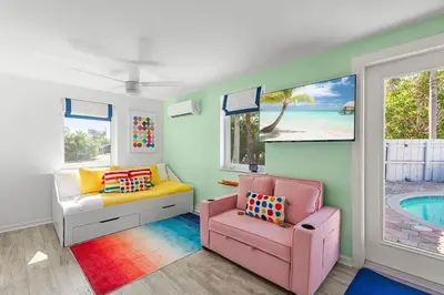 a living room with a pink chair and a pool at Chic Getaway Near Wilton Drive l Your Urban Escape in Fort Lauderdale