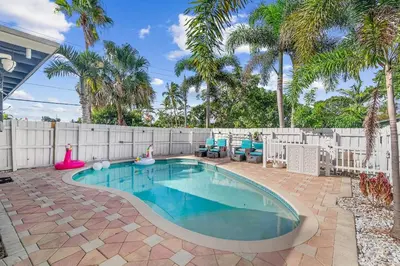 a swimming pool in a backyard with a fence and palm trees at Chic Getaway Near Wilton Drive l Your Urban Escape in Fort Lauderdale