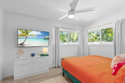 a bedroom with a bed and a flat screen tv at Chic Getaway Near Wilton Drive l Your Urban Escape in Fort Lauderdale