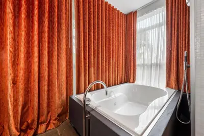 an orange shower curtain in a bathroom with a tub at Villa Nova in Miami