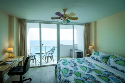 a bedroom with a bed and a desk with a ceiling fan at Castle 929 Stunning ocean view, pool, beach access, tennis, free parking in Miami Beach