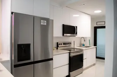 a kitchen with a stainless steel refrigerator and a tv at Villa Roads - Ideal Stay in Miami - King - Bed Parking - Near Airport, Brickell, Coconut Grove, Little Havana, Wynwood & Calle 8 in Miami