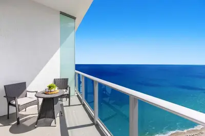a balcony with a table and chairs and the ocean at 2BR Ocean View Balcony & Pool in Hollywood