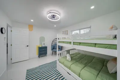 a bedroom with a bunk bed with a green couch at Home with Games Pool Paradise in Fort Lauderdale