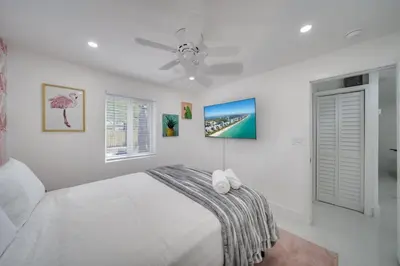 a white bedroom with a bed and a ceiling fan at Home with Games Pool Paradise in Fort Lauderdale