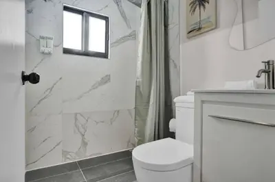 a white bathroom with a toilet and a shower at Stylish Miami Suites with Self Check-in in Miami