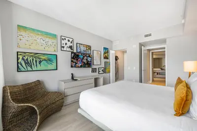 a white bedroom with a bed and a chair at Beautiful Views From a Comfortable Condo with Beach Access! in Hollywood