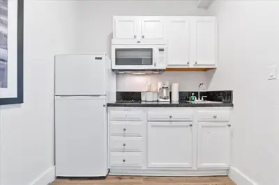 a white kitchen with a refrigerator and a microwave at South of Fifth Studio Steps to Beach on Ocean Drive in Miami Beach