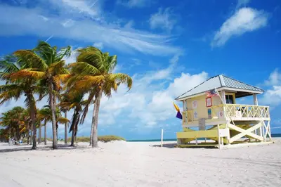 a yellow house on a beach with palm trees at Key Biscayne Beach Vacation in Miami
