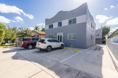 a white car parked in a parking lot in front of a building at Magical 2 BR Apartment 5 mins to Brickell Best Area in Miami in Miami