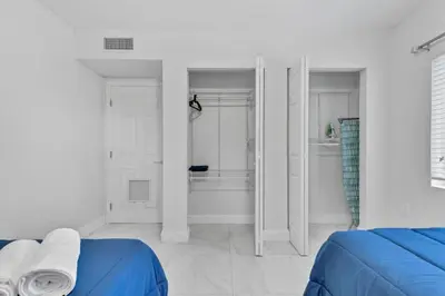 a white bedroom with a blue bed and a shower at Celeste House Enjoy Caribbean 2 BR APT in Miami