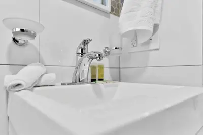 a bathroom sink with a faucet and towels at Celeste House Enjoy Caribbean 2 BR APT in Miami