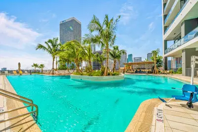 a large swimming pool with palm trees in a city at Luxury Condo on 44th Floor - Downtown Plus Parking in Miami