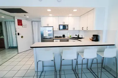 a kitchen with white cabinets and white bar stools at Castle 1133 Ocean view studio, Pool and Beach Access, FREE Parking, Tennis and more! in Miami Beach