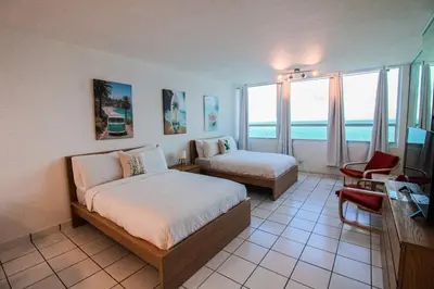a hotel room with two beds and a table and chairs at Castle 1133 Ocean view studio, Pool and Beach Access, FREE Parking, Tennis and more! in Miami Beach