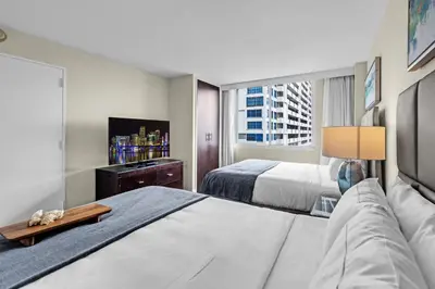 a hotel room with two beds and a tv at Gallery One Resort Access Fort Lauderdale Beach in Fort Lauderdale