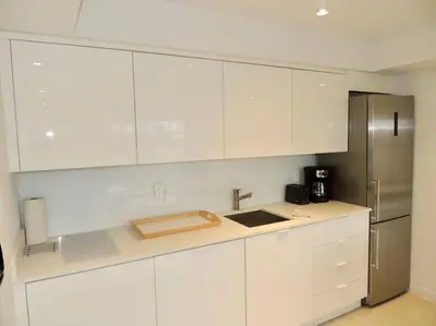 a kitchen with white cabinets and a stainless steel refrigerator at 2BR in Heart of SoBe with Parking in Miami Beach