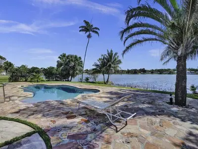 a swimming pool with a chair and a palm tree at Casa Ocaso in Miami